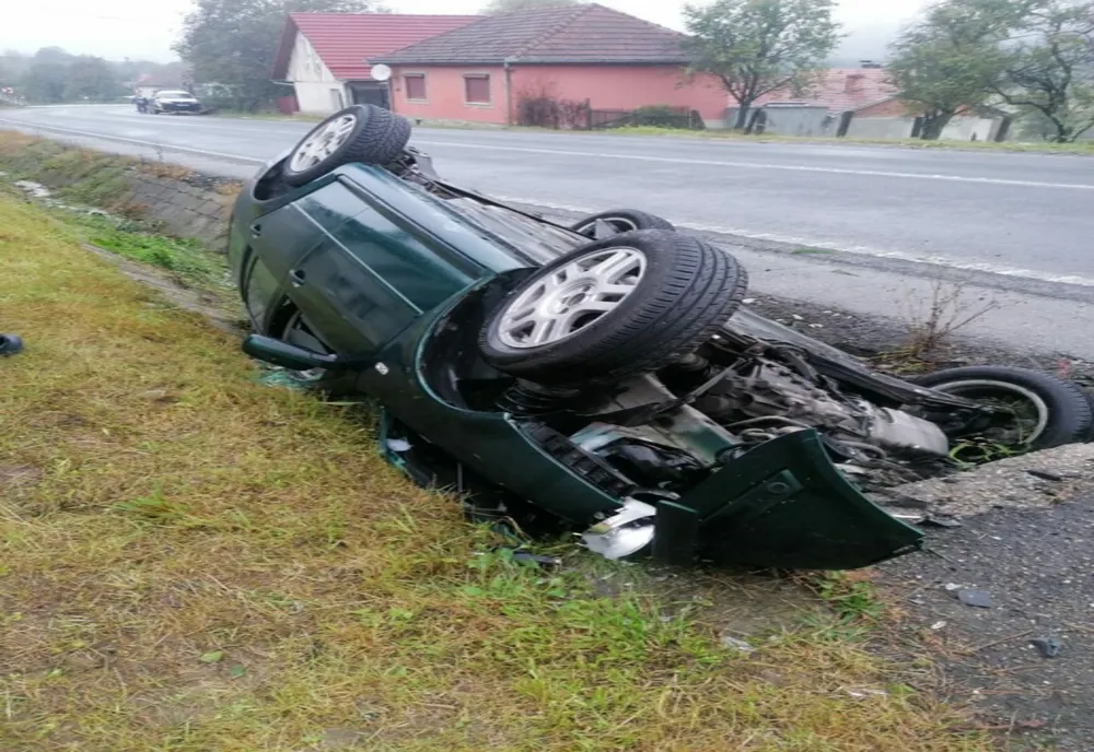 Mașină răsturnată cu roțile în sus, oameni răniți